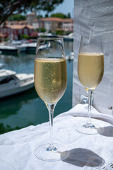 Drinking of French brut champagne sparkling wine in glasses in yacht harbour of Port Grimaud near Saint-Tropez, French Riviera vacation, France