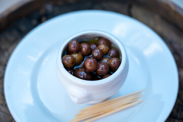Small pickled brown olives as pairing for red dry beaujolais wine served outdoor in France,...