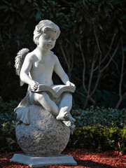 Stone child angel reading a book on a sphere