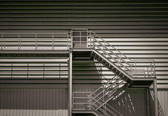 Side view of an external metal staircase as an Fire escape route at modern warehouse building. Interesting architectural elements, Emergency exit concept, Selective focus.
