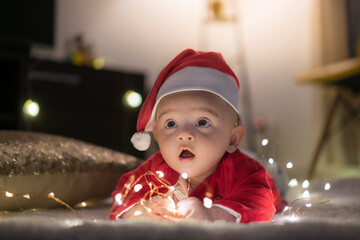 child in santa claus hat and fairy lights