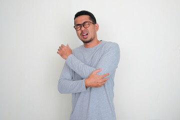 Adult Asian man touching his left hand elbow with in pain expression