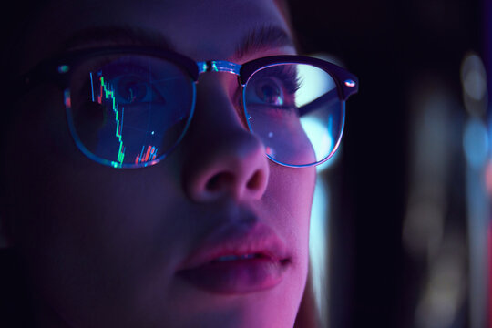 Close up view of girl's eyes in glasses looking at pc screen with computer reflection at eyewear. Using internet, working online. Technology, AI, business