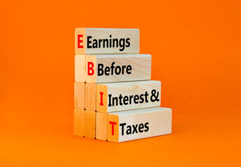 EBIT symbol. Concept words EBIT earnings before interest and taxes on wooden block on beautiful orange background. Businessman hand Business EBIT earnings before interest and taxes concept. Copy space