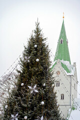 Decorated Christmas tree and church bell tower isolated on sky background, Dobele, Latvia