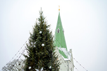 Decorated Christmas tree and church bell tower isolated on sky background, Dobele, Latvia