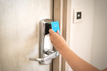 Action of a human hand is using hotel room keycard to unlocking the door. Technology object, close-up and selective focus.