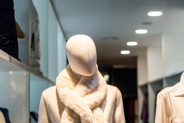  Female mannequin without a face, behind the window of a boutique