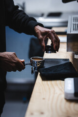 Hands of a black young man making coffee with an espresso machine