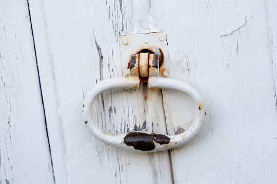 poign&eacute;e de porte ancienne et rouill&eacute;e avec de la peinture blanche craquel&eacute;e