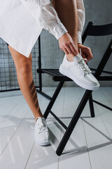 Perfect female legs in white classic sneakers. Beautiful female legs in summer shoes in white shoes.
