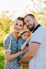 Fototapeta premium a mom and a dad with a baby daughter in a blooming spring garden. 