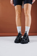 Beautiful female legs in leather black lace-up oxford shoes. Female legs with fashionable shoes and white socks. Casual black women's shoes