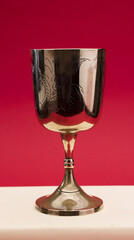 beautiful golden chalice on light beige bible with red background