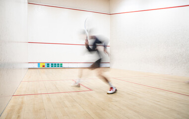 Fototapeta na wymiar Squash player in action on a squash court (motion blurred image; color toned image)