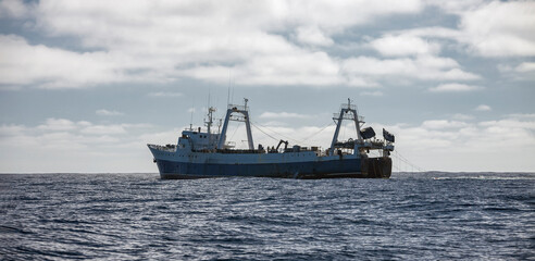 Large fishing trawler conducts industrial fishing in the open ocean.