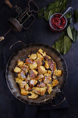 Traditioneller österreichisch Kaiserschmarren mit Zwetschgen und Rosinen serviert als Draufsicht in einer rustikalen schmiedeeisernen Bratpfanne 