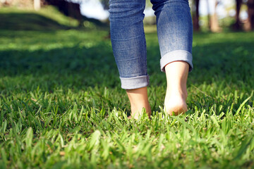 Asian woman walking barefoot on the grass to feel the nature contributes to making people feel at peace have more mental stability. soft and selective focus.      