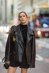 Obraz premium woman in stylish black outfit standing near blurred cars on street in New York city