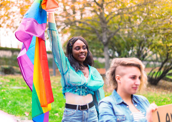 African girl holding the flag of the lgbt community in her hands while protesting for her rights.