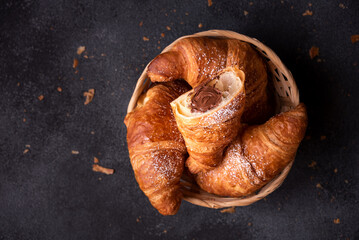 Delicious sweet croissant with chocolate on dark background