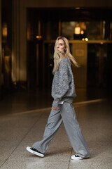 full length of young and stylish woman in grey outfit walking on street of New York