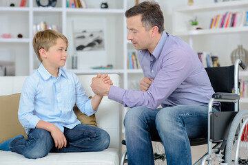 Obraz premium dad in a wheelchair playing arm wrestling