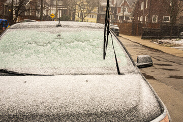 Ice covered windscreen on a passenger car with wipers raised. Shot on a residential street in the Toronto Beaches in December. - obrazy, fototapety, plakaty
