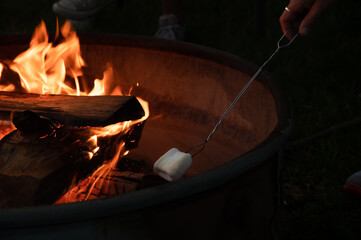 Roasting a marshmallow on a campfire at night 
