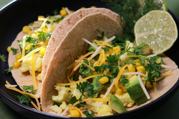close up of keto tortilla breakfast with scrambled eggs, avocado, cheese and cilantro 