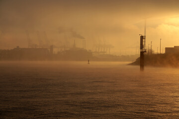 Dramatischer Sonnenaufgang über den Hamburger Hafen mit Nebel und Wolken im Winter 