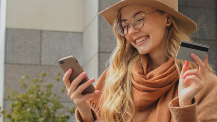 Caucasian 30s girl close-up 20s woman lady female with mobile phone and bank credit card buying...
