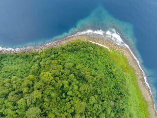 A lush, tropical island is fringed by a coral reef in the Solomon Islands. This beautiful country...