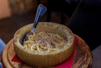 Fresh pasta with truffle in pecorino cheese wheel in restaurant, Florence, Italy