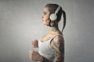 portrait of a young woman in profile with tattoos listening to music