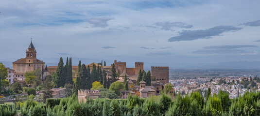 Fototapeta premium Amazing panorama of Granada city and Alhambra's Alcazaba fortress. Scenic view from Generalife gardens on a sunny day with blue sky above. Granada, Andalusia, Spain. 