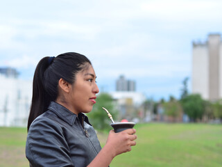 Mujer joven, latina morena tomando yerba mate en el atardecer sonriendo © Teo 