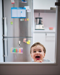 Toddler playing behind the glass of the kitchen door