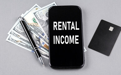 Credit card and text RENTAL INCOME on smartphone with dollars and pen. Business