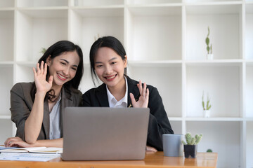 Two young Asian business woman talk, consult, discuss working with new startup project idea presentation analyze plan marketing and investment in the office.