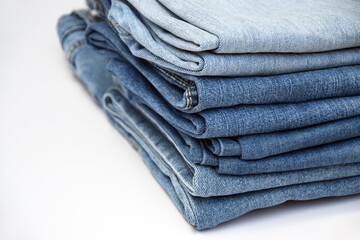 Lots of jeans pants in a stack. Denim background.