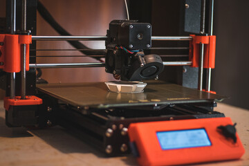 Technological hi-teg tool for making new things. A black and red 3D printer at work. The object is created by laying down continuous layers of material in additive processes
