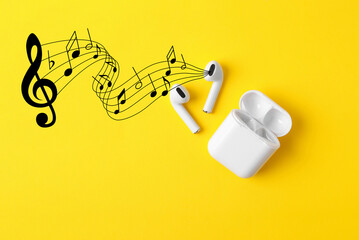 Staff with music notes and treble clef flowing from white wireless earphones on yellow background,...