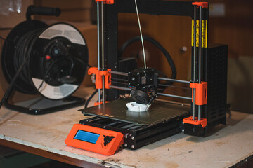 Technological hi-teg tool for making new things. A black and red 3D printer at work. The object is created by laying down continuous layers of material in additive processes