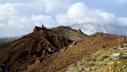 Winter in Teide National Park.View on rocks and Teide volcano in snow and clouds in the distance,Tenerife,Canary Islands,Spain.Selective focus.