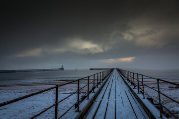 Obraz na płótnie Canvas A freezing, snowy morning at Blyth beach at the old wooden Pier stretching out to the North Sea