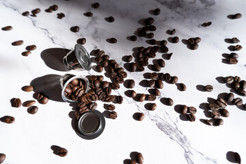 Two aluminum Reusable coffee pods and coffee beans on a wooden table