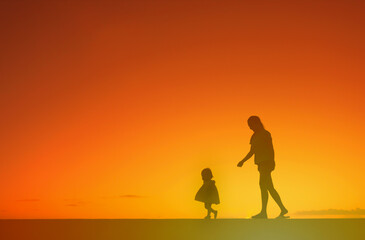 Fototapeta na wymiar Mother walking with child during golden sunset sunset 