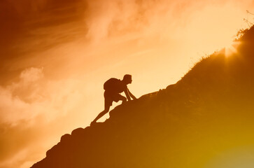 Brave man climbing up steep rocky mountain cliff.