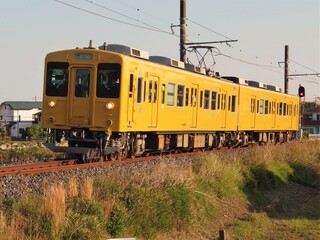 Obraz premium 田舎を走る夕日に照らされた黄色いワンマン電車